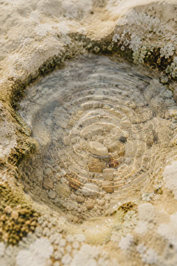 Close-up photograph of clear water rippling over pale stones.